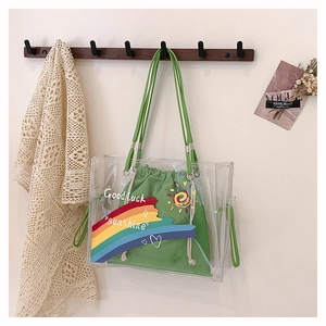 Detail of clear PVC tote with green canvas drawstring bag featuring rainbow graphics