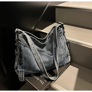 Close-up of vintage washed denim tote bag showing pockets and silver metal buckle details