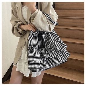 Detail of checkered tote bag with tiered ruffles and drawstring closure in street style