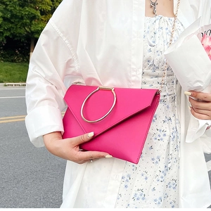 Détail de la pochette fuchsia avec poignée en anneau doré et bandoulière chaîne