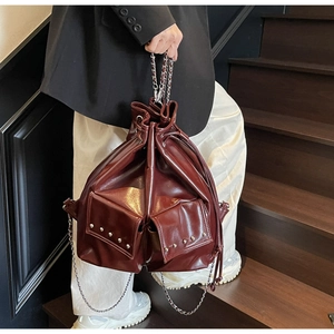 Detail of burgundy faux leather bucket bag with silver studs and chain strap handle
