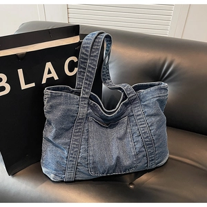 Detail shot of blue washed denim tote bag showing fabric texture and front pocket stitching