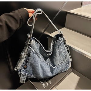 Detail of vintage blue denim tote bag with side metal buckle and adjustable strap