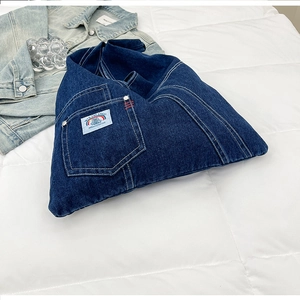 Detailed view of dark blue denim tote bag with vintage embroidery patch on white texture