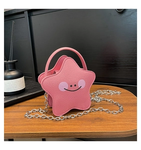 Macro detail of pink star-shaped bag with cartoon face and pebbled faux leather texture