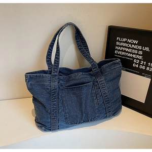 Detailed view of dark blue washed denim tote bag with front pocket and sturdy top handles