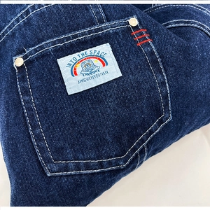 Detail of blue denim fabric with Into The Space label and contrast white stitching