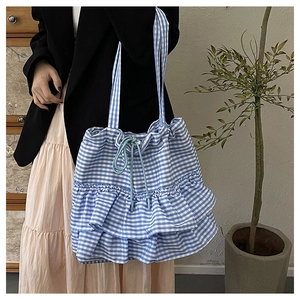 Detail of blue and white checkered canvas tote bag with drawstring closure and tiered ruffles