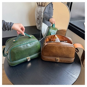Close-up of double-layer vintage leather makeup bags in green and caramel with gold zippers