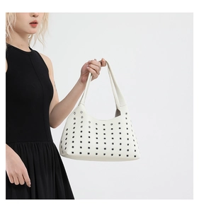 Detail der weißen hohlen Nietentasche mit silbernen Ösen auf strukturiertem Leder