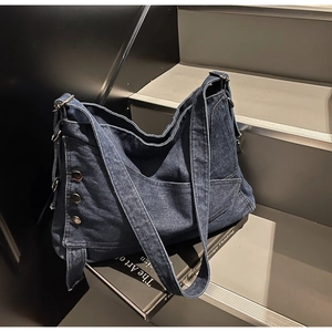 Close-up of vintage blue denim tote bag featuring retro metal rivets and wide strap