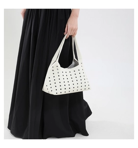 Detail einer weißen Lederhandtasche mit Nieten an einem Model in Nahaufnahme
