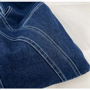 Macro shot of high-quality dark blue denim fabric with precise white contrast stitching
