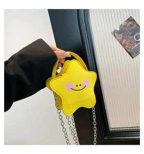 Detail of yellow star-shaped leather mini bag with smiley face and silver chain strap
