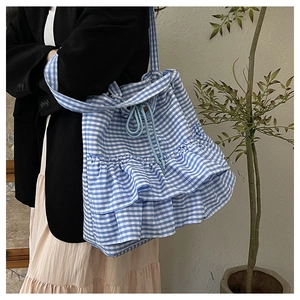 Detail of blue and white checkered canvas tote bag with ruffled edges and drawstring closure