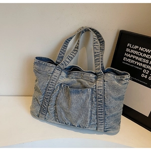 Detailed view of the washed light blue denim tote bag with a front square pocket