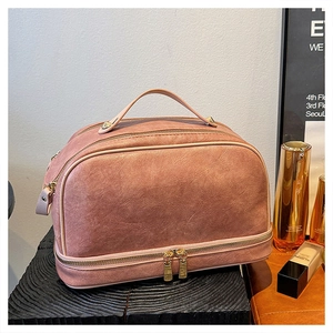 Detail view of the layered dust pink leather makeup bag with gold hardware and top handle