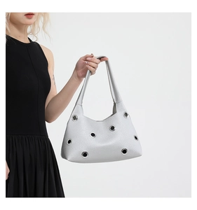 Close-up of silver rivet cutout shoulder bag on model wearing a black dress