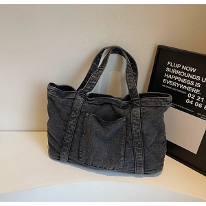 Close-up of vintage dark gray denim tote bag featuring a front pocket and washed texture