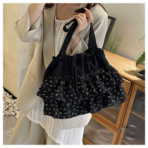 Detalle de bolso tote floral negro con volantes a capas y práctico cierre de cordón
