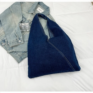 Detailed view of dark blue denim tote bag with diagonal stitching on a white quilted surface