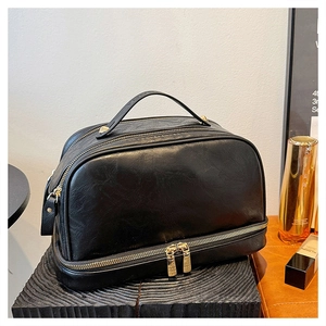 Detail of vintage black leather cosmetic bag with gold zippers on wooden stand