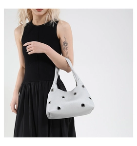 Nahaufnahme der silbernen Hobo-Tasche mit großen Metallösen und Kunstleder-Textur