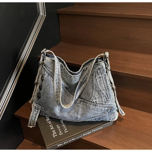 Detail of vintage denim tote bag featuring side pockets and metal D-ring on wood stairs