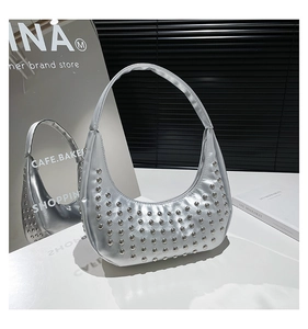 Silberne Hobo-Tasche mit Nieten im Punk-Stil auf einer minimalistischen weißen Oberfläche