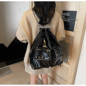 Close-up of black glossy PU backpack with silver studs and chain straps detail