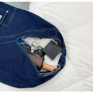 Macro detail of dark blue denim tote bag with white stitching and large storage capacity