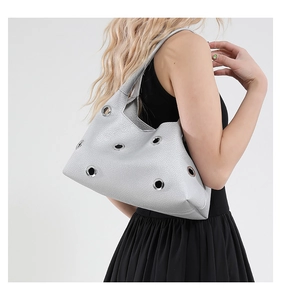 Macro detail of silver leather shoulder bag featuring large polished metal eyelets