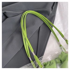 Detail of transparent PVC tote bag with green leather straps and drawstring inner pouch