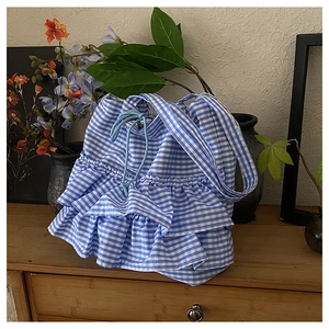 Detail of blue and white checkered tote bag featuring layered ruffles and drawstring