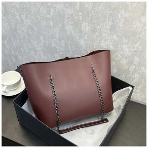Detail view of burgundy tote bag with silver chain straps and premium gift packaging
