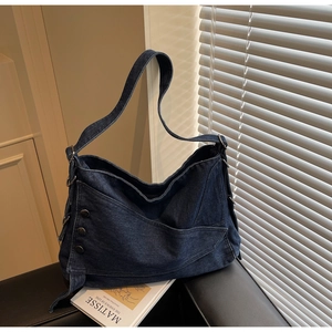 Detailed texture of vintage denim tote bag featuring retro metal buttons and frayed edges