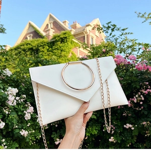 Détail de la pochette enveloppe blanche avec poignée anneau dorée et sa chaîne élégante