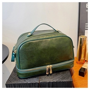 Detail of vintage green makeup bag with dual gold zippers and smooth top handle