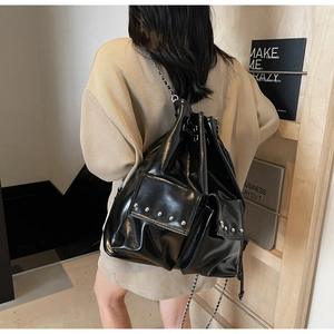 Glossy black rivet bucket backpack with chain straps shown on model from behind