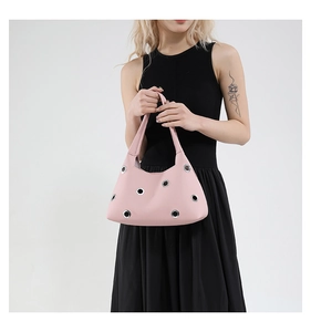 Detail of pink pebbled leather shoulder bag with large silver metal eyelets and rivets