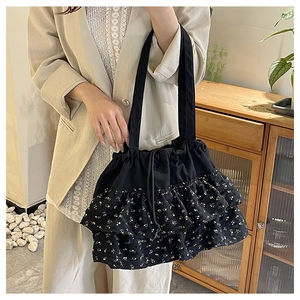 Detalle del bolso tote de flores negro con elegantes capas de volantes y cierre de cordón
