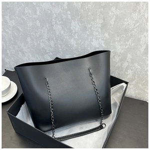 Detail view of large black tote bag featuring matte leather and metal chain shoulder strap