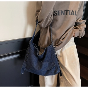 Detail of dark blue denim hobo bag featuring decorative black buttons and buckle straps