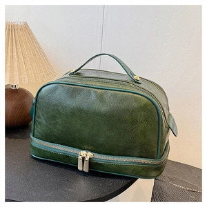 Detail view of deep green vintage oil wax leather makeup bag with gold hardware double zippers