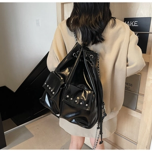 Side view of a glossy black waterproof bucket backpack with rivet details and chain strap