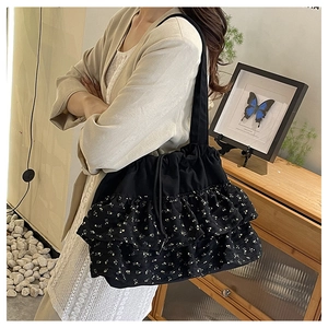 Detalle del bolso tote floral negro con volantes y cordón ajustable al hombro