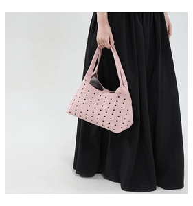 Detail view of pink rivet hollow underarm bag worn by a model in a black dress