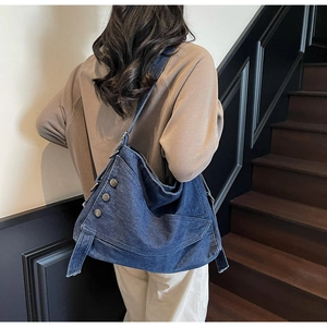 Detail of blue denim tote bag with metal buttons and decorative belt on the side