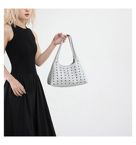 Detail view of silver hollow-out shoulder bag with metal rivet eyelets and wide handle
