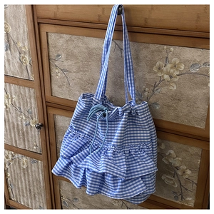 Detail of blue vichy plaid canvas tote bag featuring ruffled layers and drawstring closure